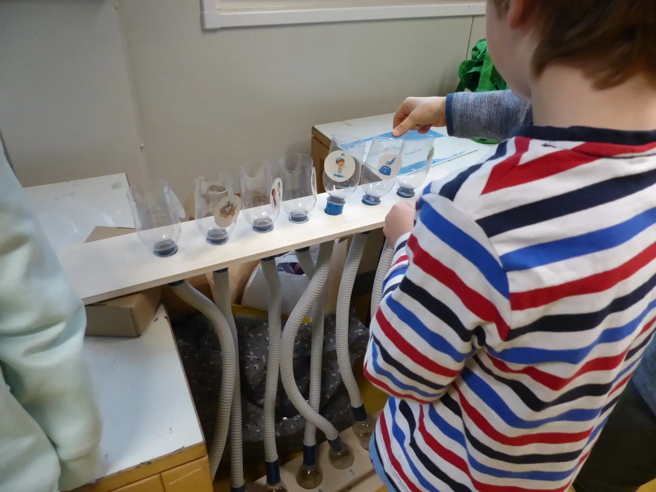Kind steht vor einem Experiment mit Flaschen und Schl&auml;uchen