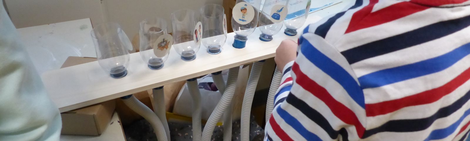 Kind steht vor einem Experiment mit Flaschen und Schläuchen